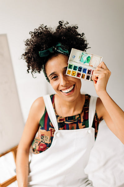 Woman covering her eye with a palette in her art studio