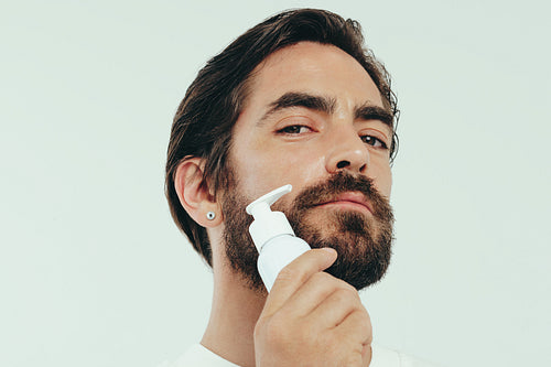 Doing skincare with face serum: Handsome man using a facial product in his skincare routine