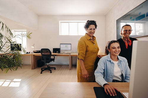 Coworkers looking at project scope on computer in a modern office setting