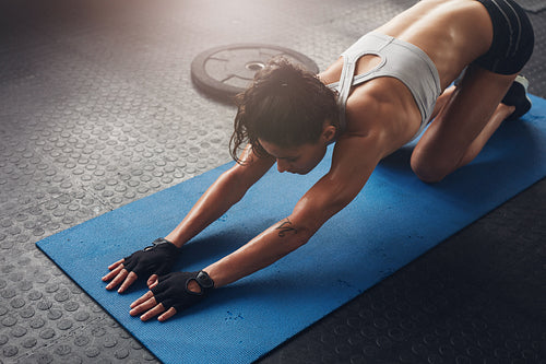 Woman on fitness mat doing stretching workout at gym.