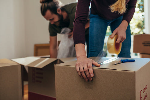 Close up of a woman applying adhesive tape on a packing box