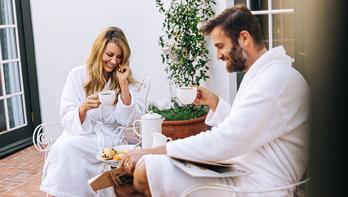 Smiling couple having tea in morning robes