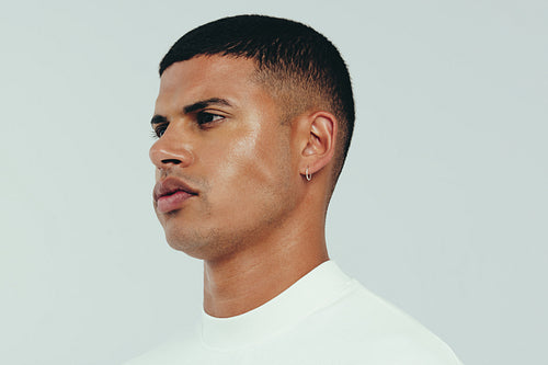 Young man with flawless and radiant skin standing in a studio