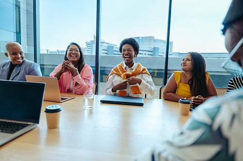Joyful team meeting at a modern agency with diverse professionals laughing around a conference table