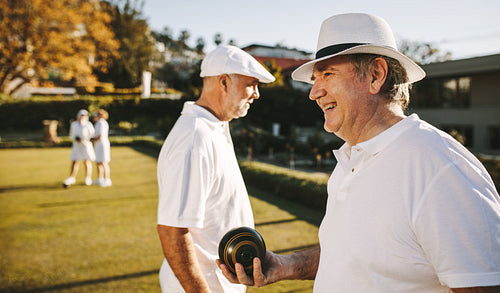 Elderly man standing in a lawn holding a boules