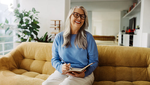 Senior woman writes in a journal at home