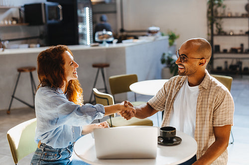 Business partners shaking hands during a lunch meeting in a coffee shop