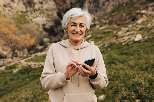 Cheerful senior woman using a smartphone outdoors