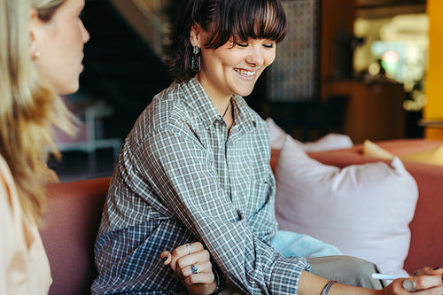 Smiling student engaging in a friendly conversation with a peer in a cozy lounge area