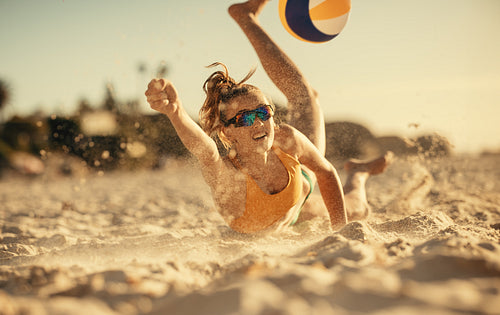 Dynamic female athlete jumping for the ball on sandy beach court in summer games