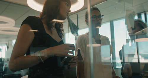 Female executives discussing over sticky notes on glass wall