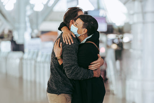 Woman receiving man at airport arrival gate