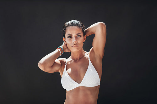 Woman in white bikini posing on black background