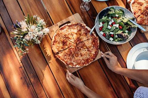 Woman setting the pizza on table for dinner