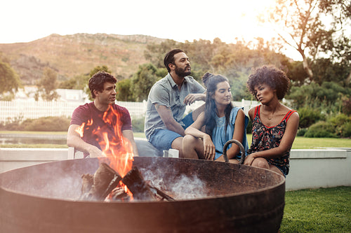Two young couple sitting in backyard with a camp fire