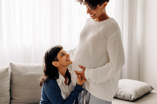 Pregnant lesbian couple smiling at each other