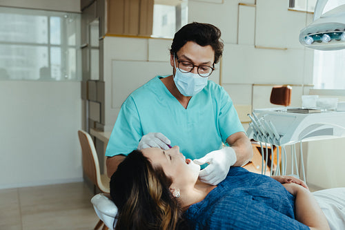 Dentist providing dental care to female patient during exam