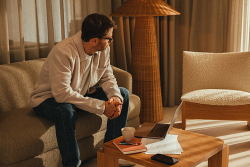 Working businessman pauses with a laptop and coffee in office lounge