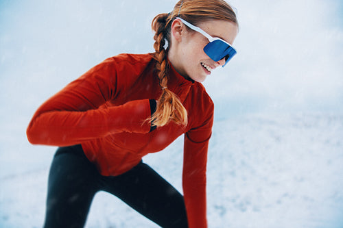 Woman runs with motivation through winter snow during outdoor fitness training