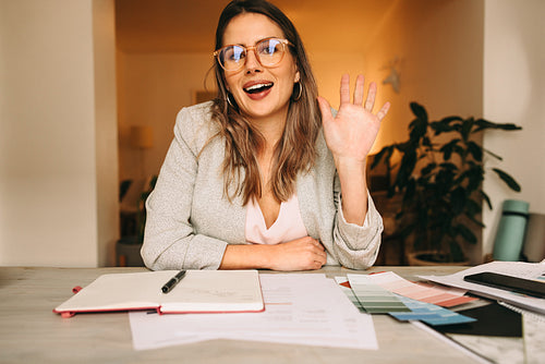 Young interior designer waving her hand during a video call
