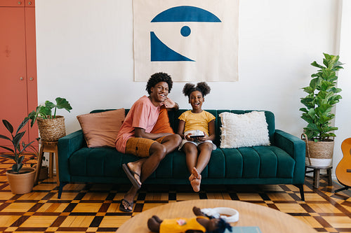 Happy siblings relaxing on the couch with a digital device