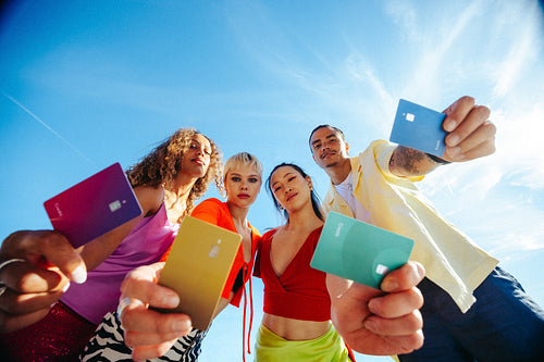 Young adults display colorful credit cards for financial independence outdoors