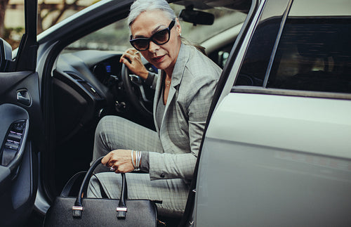 Sophisticated mature woman disembarking the car