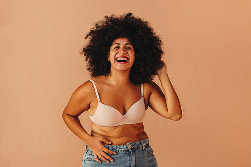 Gorgeous woman with Afro hair laughing happily in a studio