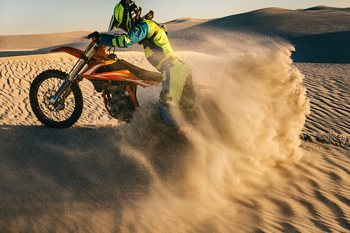 Professional motocross biker racing on sand dunes
