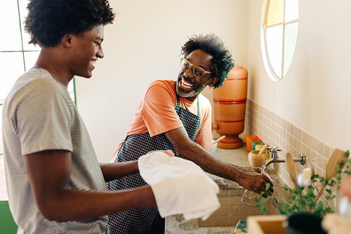 Happy father and son washing their hands in a Brazilian kitchen
