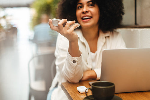 Young freelancing woman speaking on the phone in a cafe