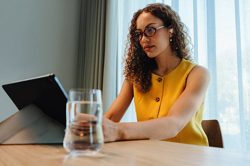 Focused african american woman using a tablet at home office desk
