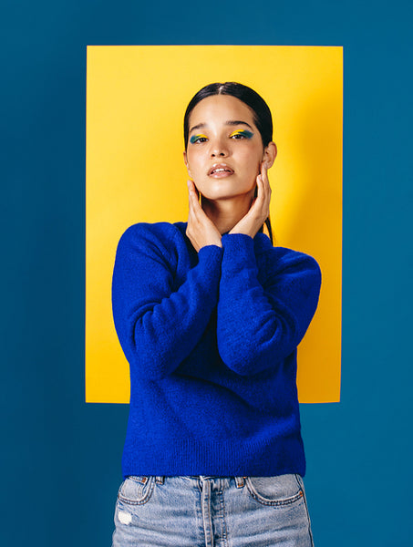 Portrait of a young woman standing in front of a geometric shape with makeup on