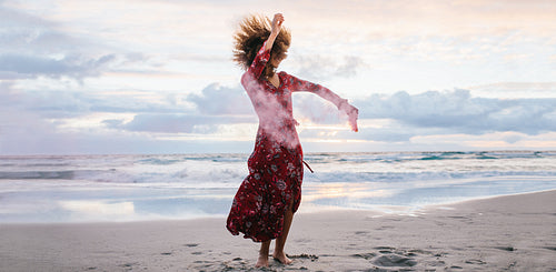 Woman dancing with smoke grenade at the beach