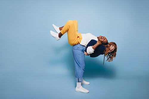 Energetic young woman carrying her best friend on her back in a studio