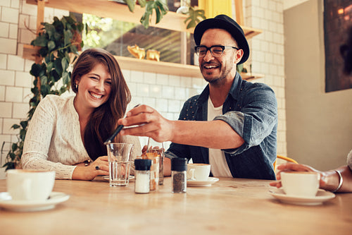 Young friends looking at smart phone while sitting in cafe