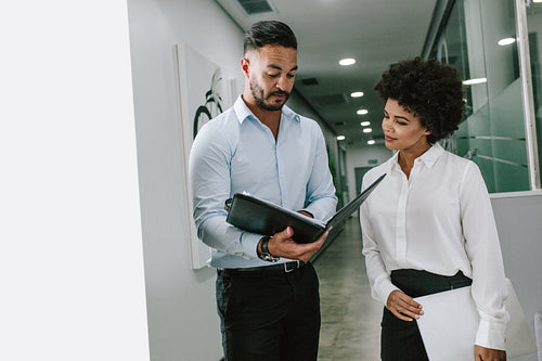 Business colleagues reviewing a file in office corridor