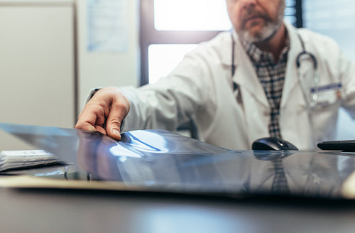 Doctor sitting in his clinic and examining medical scan