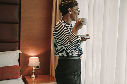 Businesswoman standing in hotel room with a cup of coffee