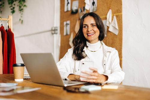 Creative business woman working with mobile technology to market her fashion design startup online