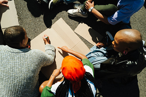 Group of individuals preparing protest signs outdoors on a sunny day