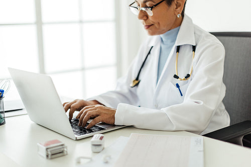 Doctor using a laptop in her office, searching for patient records on an EHR system