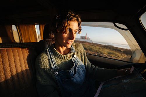 Traveling woman maps out coastal road trip in a cozy van