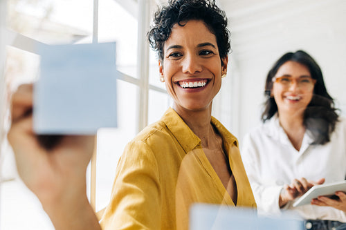 Business woman writes on sticky notes as she brainstorms with her colleague