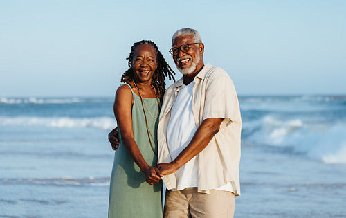 Joyful senior couple posing together on a sunny beach