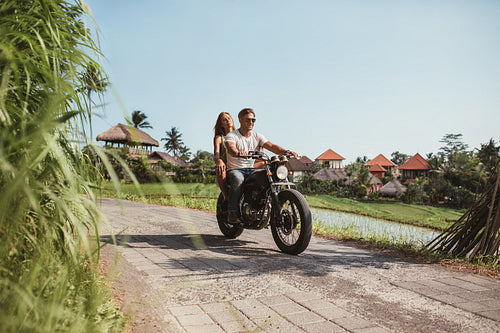 Young couple riding motorcycle on rural road