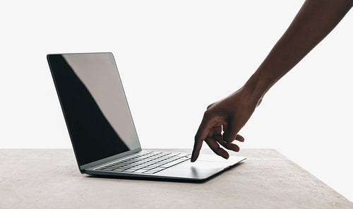 Hand reaching towards laptop with blank screen for technology mockups