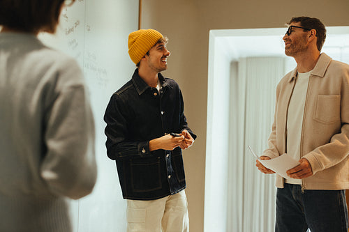 Coworkers exchange ideas by the whiteboard during an office meeting