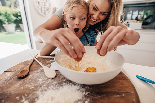 Mother and daughter making dough in kitchen