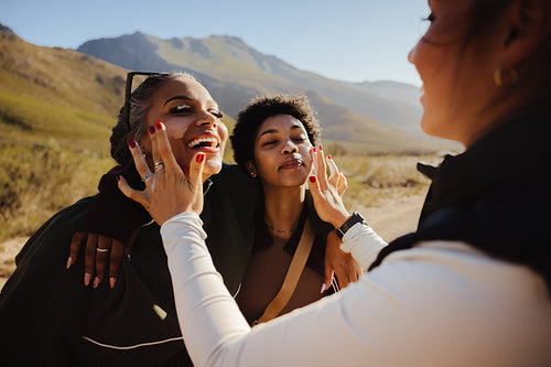 Friends applying sunscreen while hiking on a sunny day
